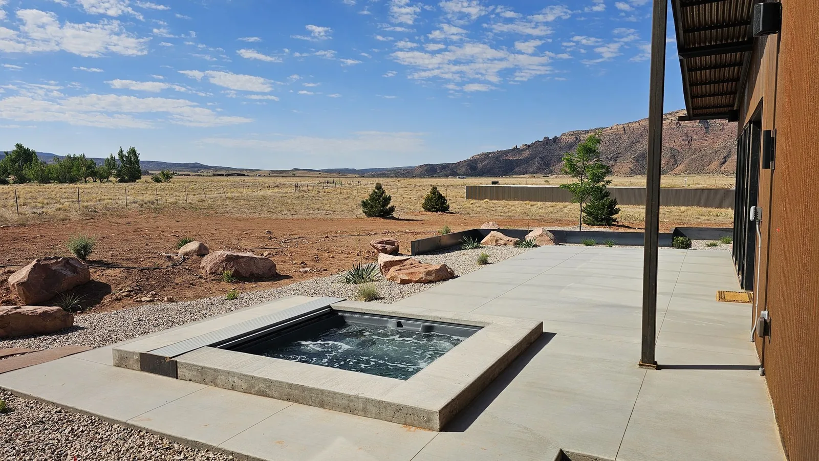 Spa set in board-formed concrete with its automatic cover rolled back along one edge